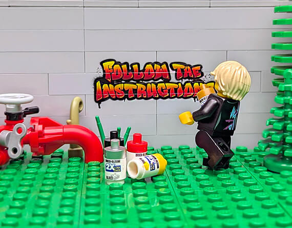 lego Minifig painting graffiti on a light bluish gray brick wall "Follow the Instructions" with a custom LEGO set of a water main in the background.